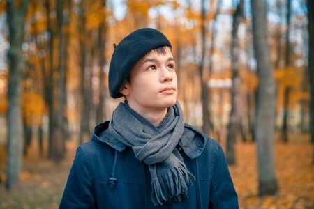 47531272 - serious teenage boy in a beret and jacket in the autumn sunny park